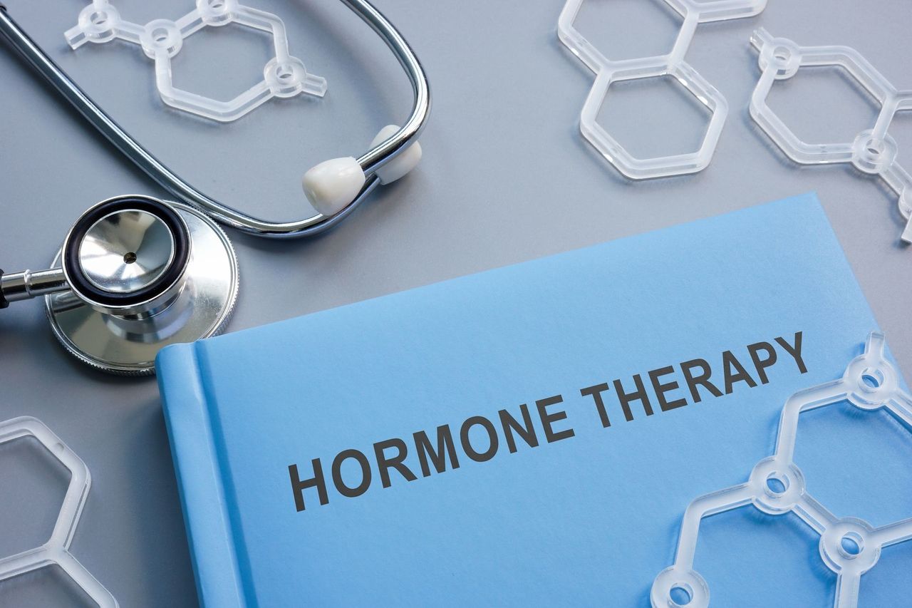 Blue folder labeled “Hormone Therapy” with a stethoscope and molecular models on a desk