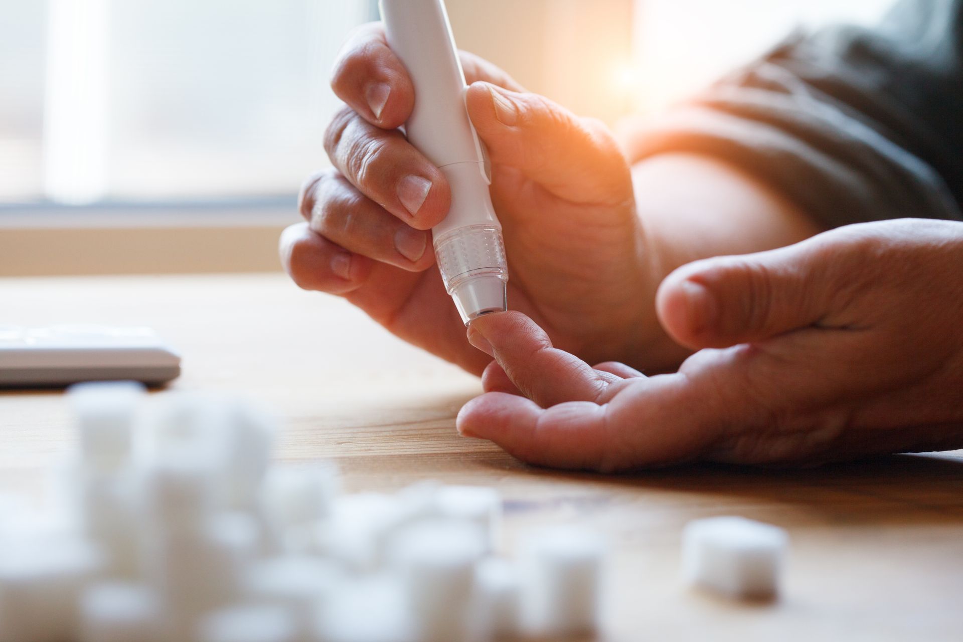 Hands being checked for pulse on a bright tabletop, with blurred pill bottles in the foreground