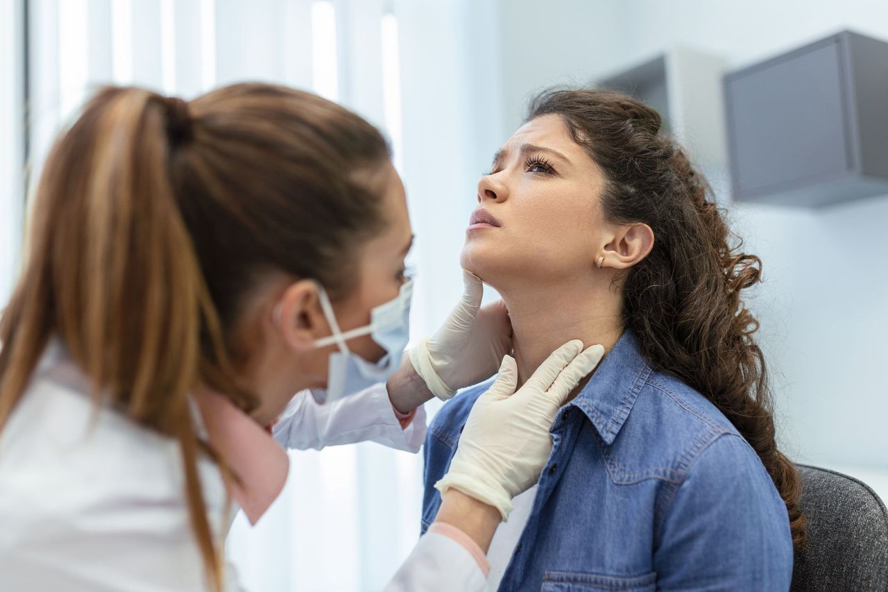 Clinician examining a patient’s neck in a medical office