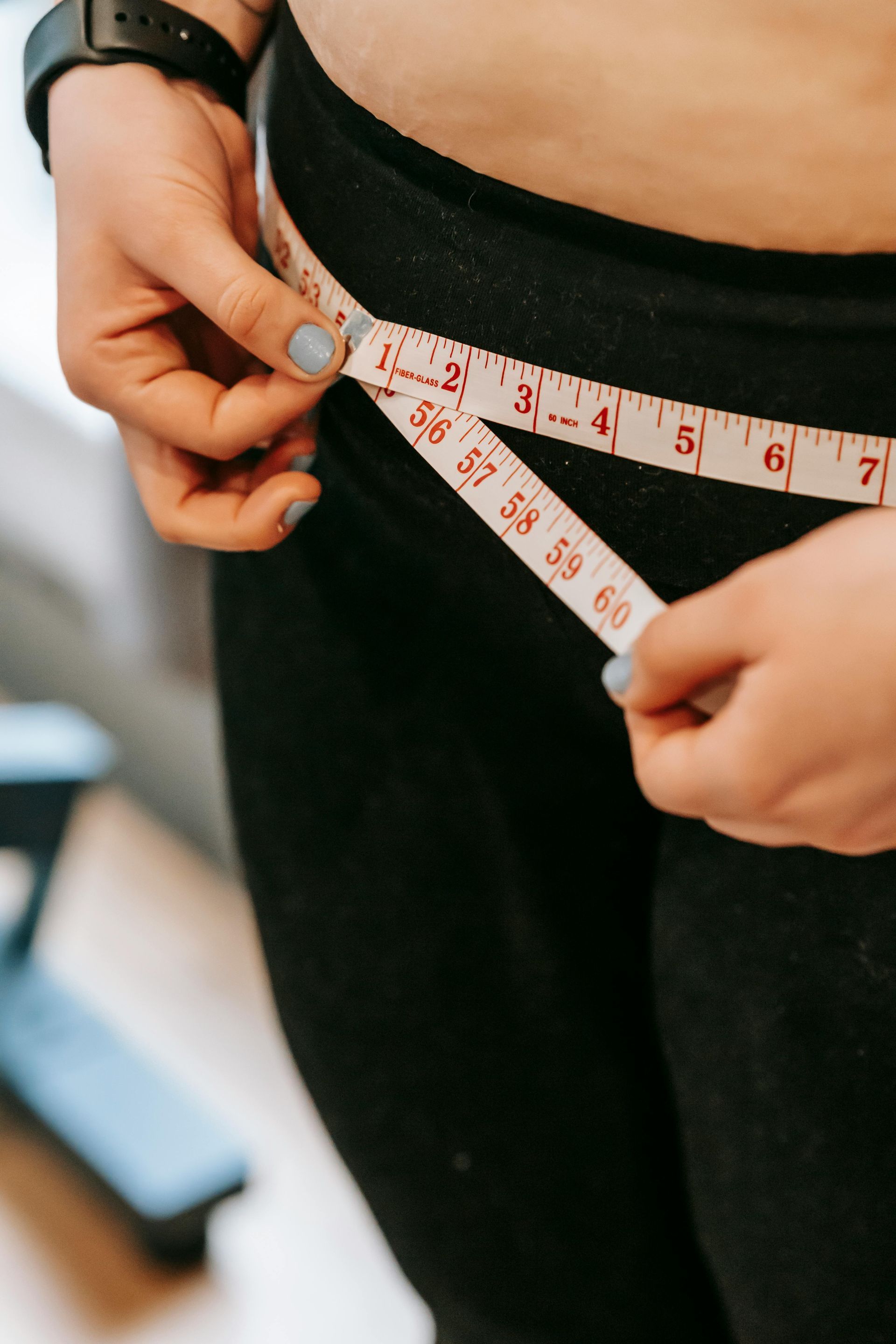 Tape measure wrapped around a waist over black leggings